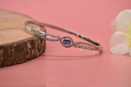 AD silver bracelet with a purple gemstone on a pink background