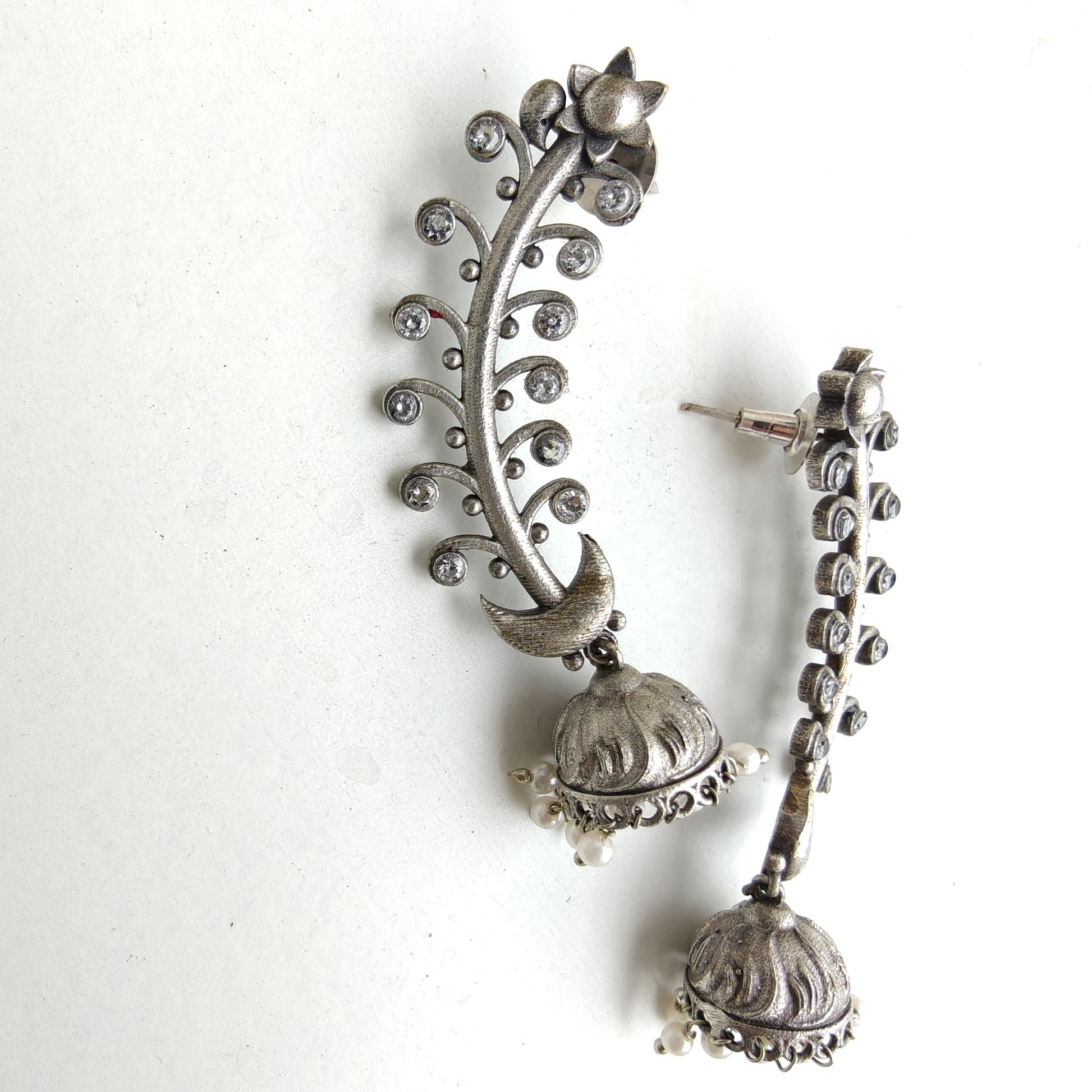 Oxidised silver floral jhumka earrings with pearl drop on a white background
