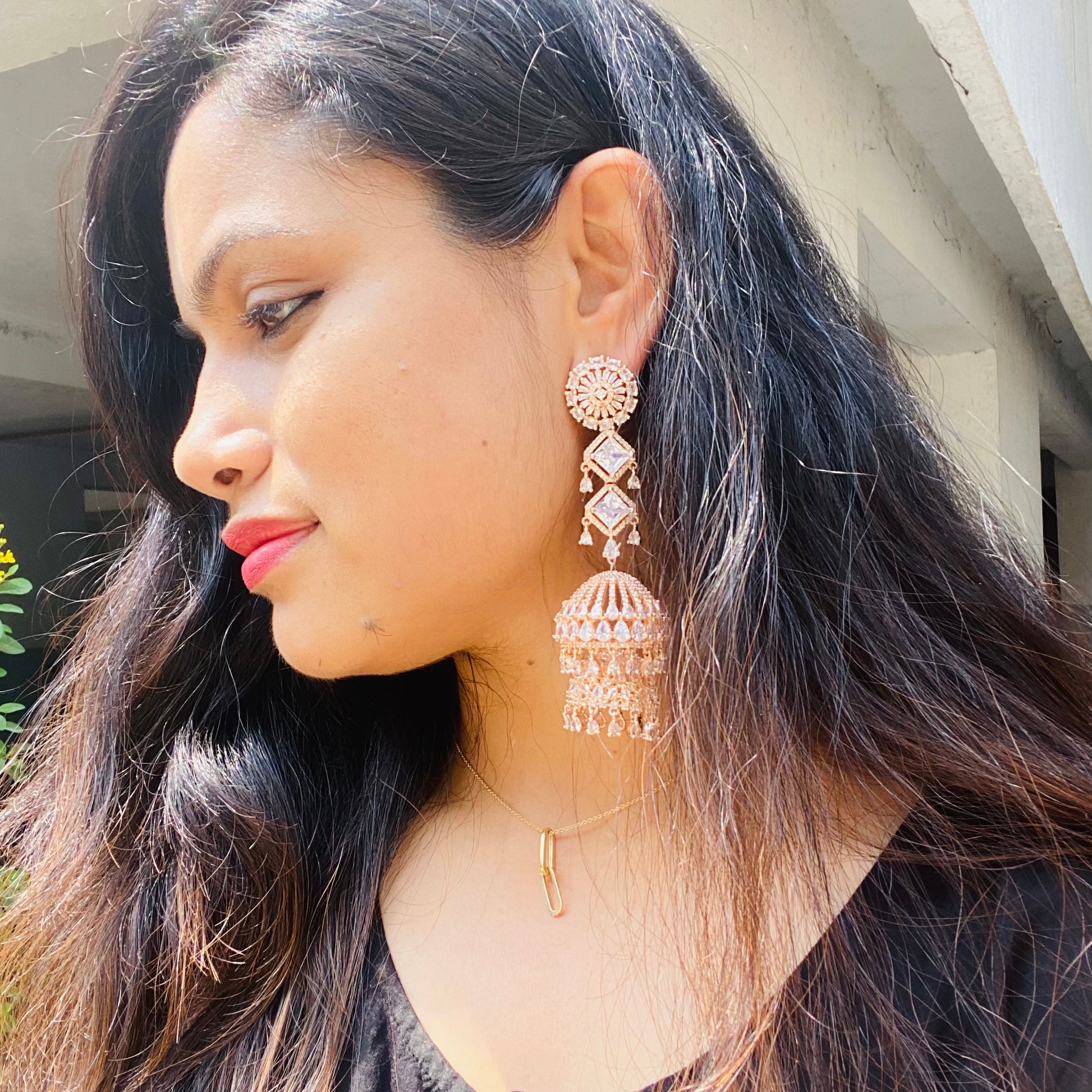 Woman wearing a large, AD Rosegold Jhumka ornate earring wearing outdoors