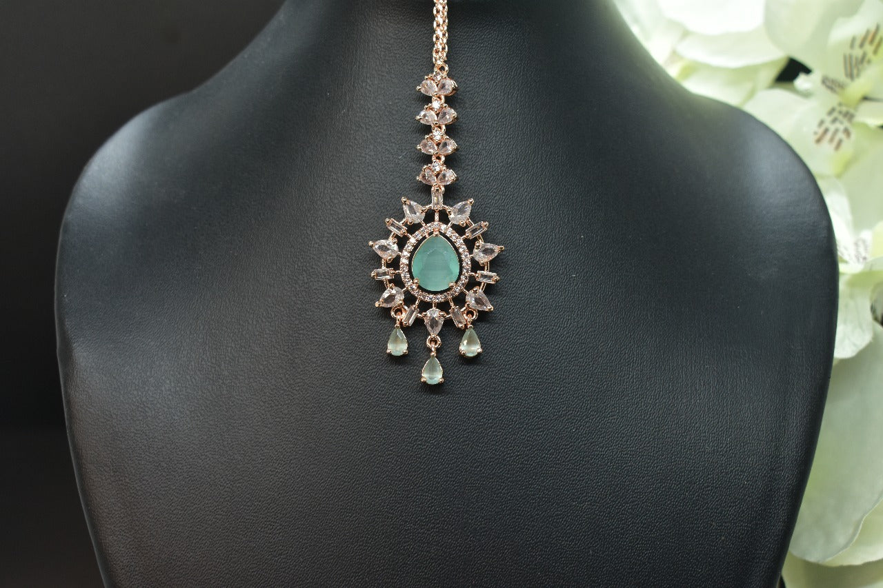 Zirconia Rosegold shaped Mangtikka with turquoise  gemstone on a black stand