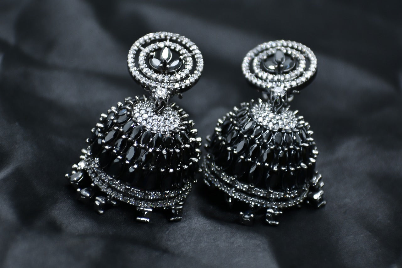 Pair of AD silver and black earrings Jhumkas on a dark background