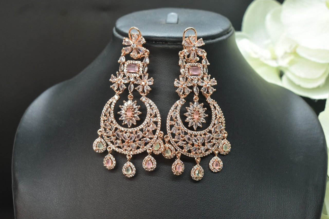 AD earrings on a black mannequin with a blurred floral background