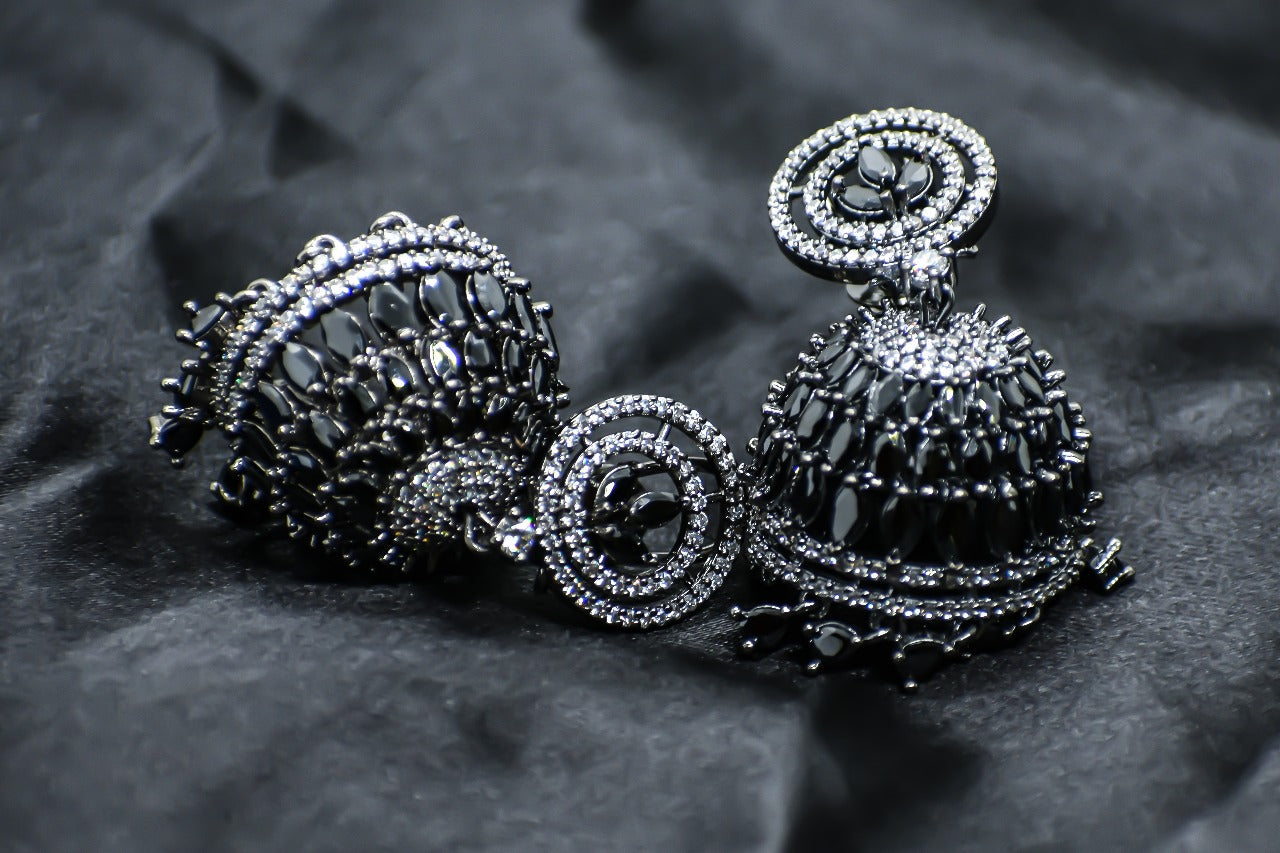 Zirconia Black stones jhumka earrings on a black fabric background