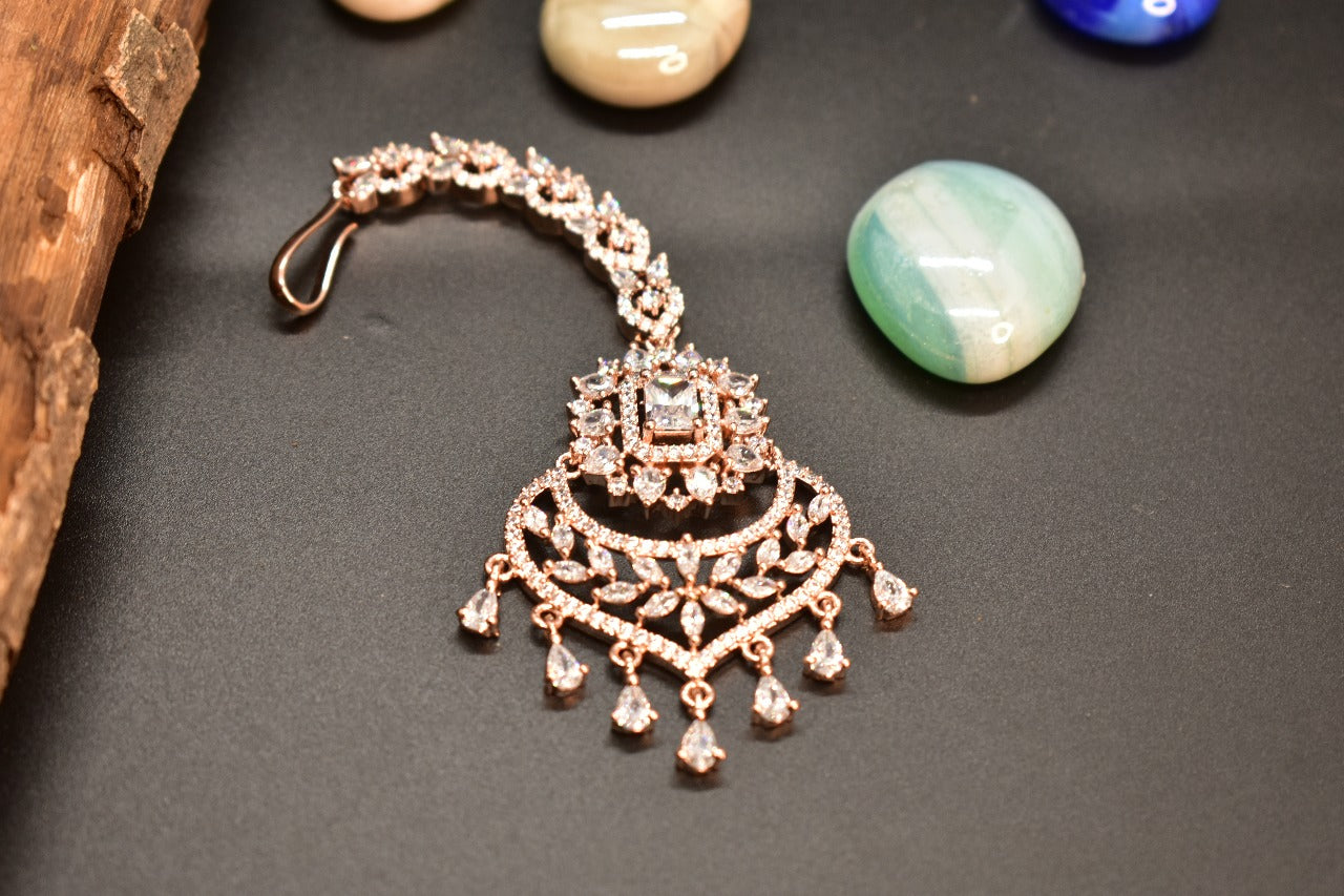 Rose gold chandelier Mangtikka on a dark surface with stones in the background