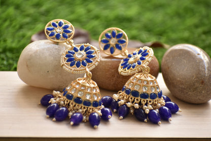 Polki Pair of blue and gold earrings on a wooden surface with a natural background