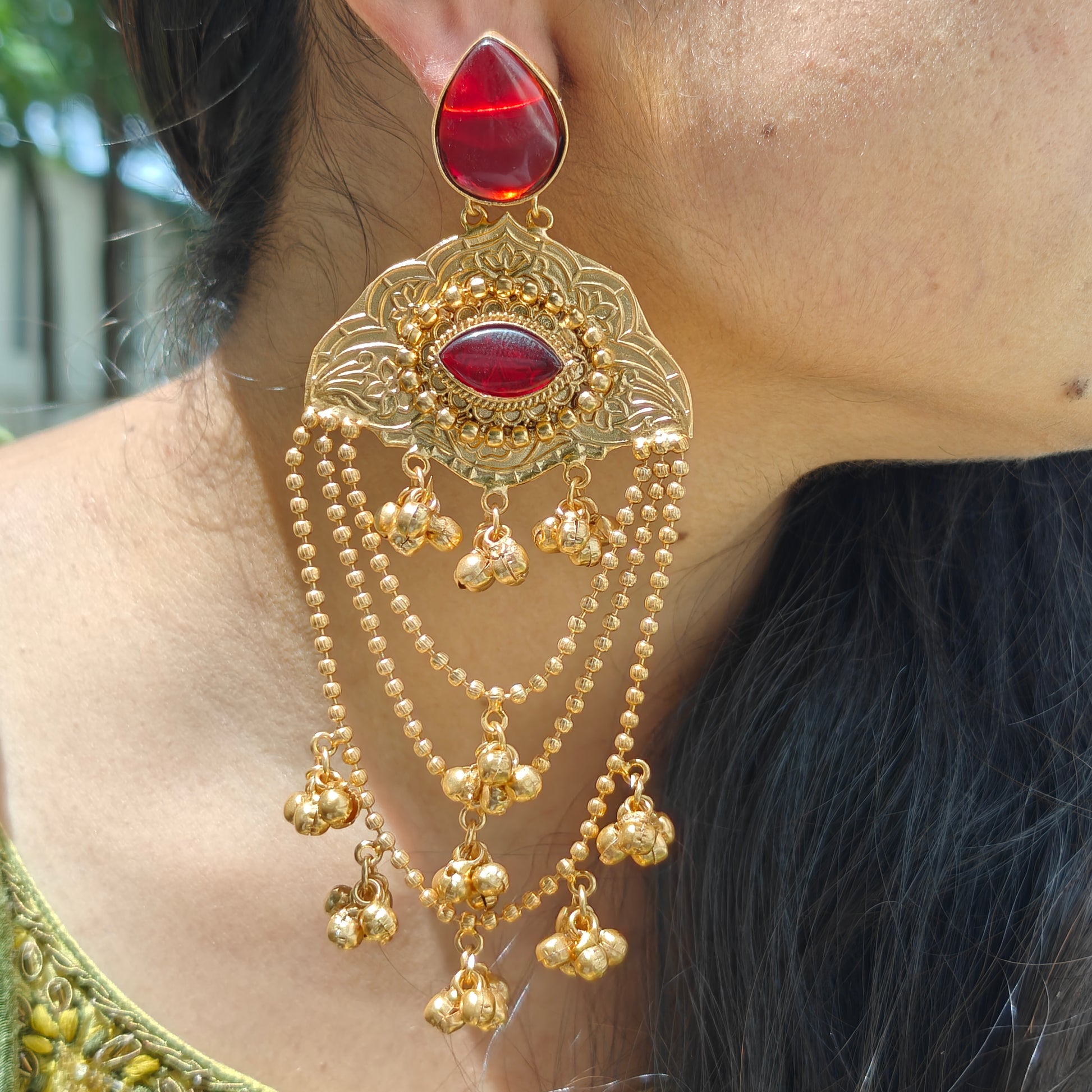 Kashmiri chain Gold Ghungroo earrings with red gemstones worn by a person