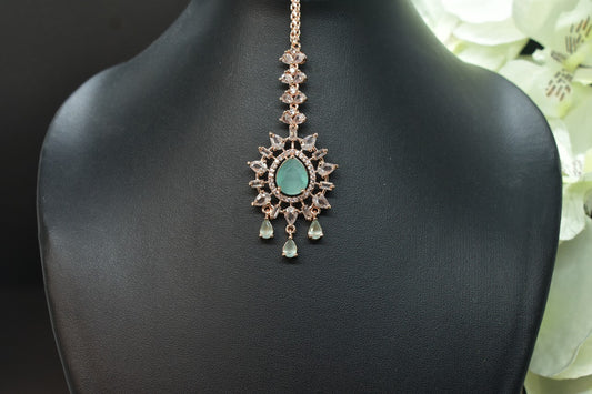 Zirconia Rosegold shaped Mangtikka with turquoise  gemstone on a black stand