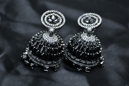 Pair of AD silver and black earrings Jhumkas on a dark background