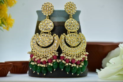 Polki Gold earrings with green and red beads on a stand with a blurred background