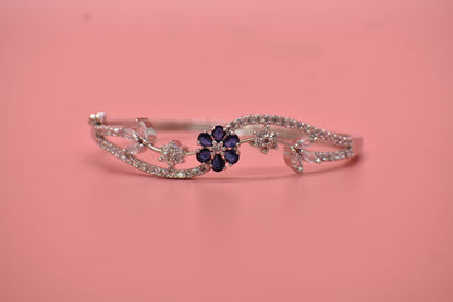 American Diamond Silver bracelet with a blue flower charm on a pink background  