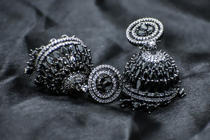 Zirconia Black stones jhumka earrings on a black fabric background