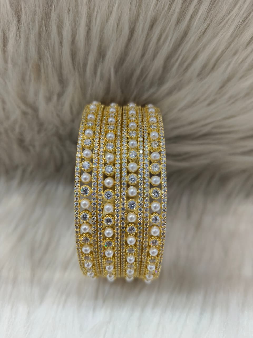 Zirconia AD Gold pearl bracelet Bangle with pearls and crystals on a fur background