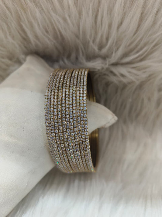 Black Gold bracelet bangle with clear stones on a white stone surface with a fur background
