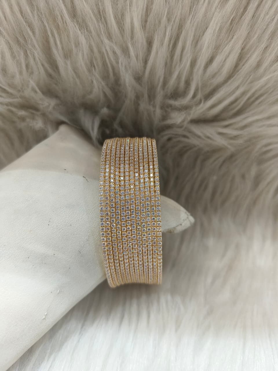 Zirconia Gold bangles with clear stones on a white surface with a fur background