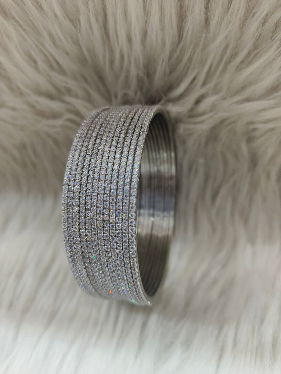 AD Rhodium Bangles with clear stones on a fluffy beige surface